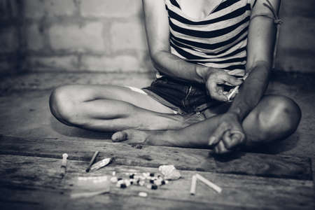 Drug addict young woman with syringe in action, Drug abuse concept.の写真素材
