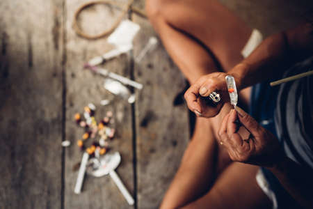 Drug addict young woman with syringe in action, Drug abuse concept.の写真素材