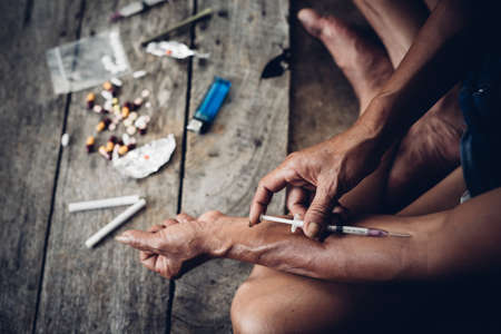 Drug addict young woman with syringe in action, Drug abuse concept.の写真素材