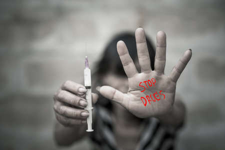 Drug addict young woman with syringe in action, Drug abuse concept.