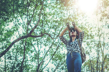 Woman with binoculars and telescope in rain forest. Hiking concept.の写真素材