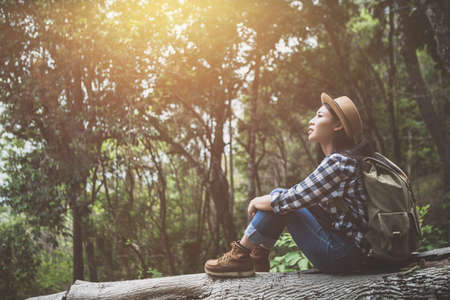 Girl traveler with a backpack sits on logs in the forest.の写真素材
