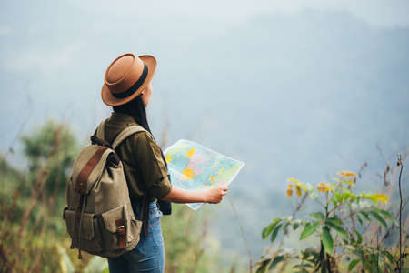 Young woman hiker with backpack watching trekking map.の写真素材