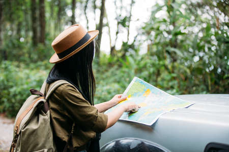 Young woman hiker with backpack watching trekking map.の写真素材