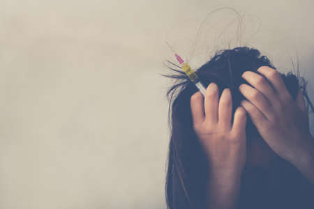 Drug addict young woman with syringe in action, Drug abuse conceptの写真素材