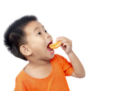 Child in orange outfit eat orange isolated on white background.の写真素材