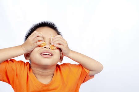 Child in orange outfit eat orange isolated on white background.
