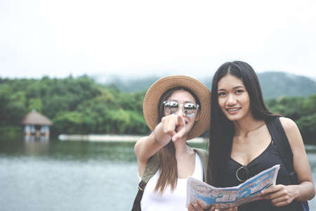 Two beautiful girls traveling with luggage at the public parkの写真素材