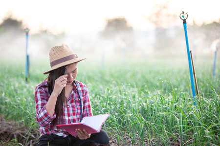 Farmers smiling women, recording happy and happy results in the onion plots with notebook