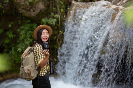 Female hikers take pictures of themselves with beautiful waterfalls. Relax after hikingの写真素材