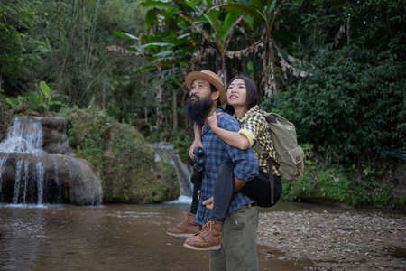 Young travelers are holding hands together, walking happily in the waterfall.