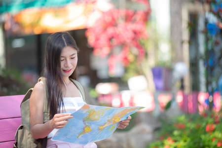 Female tourists hold a map to find places.