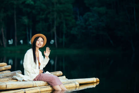 Female tourists who smile bright, happy sitting on the water's edgeの写真素材