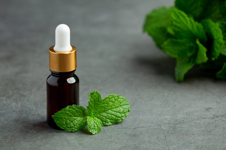 Essential oil of peppermint in bottle with fresh green peppermintの写真素材