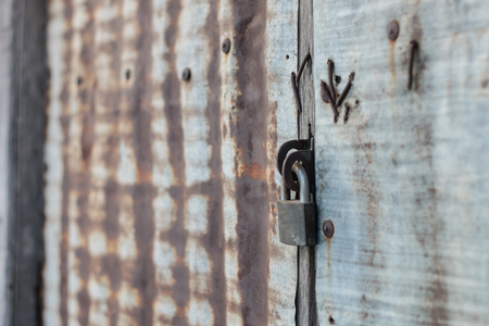 Old rusty padlock on old rusty zinc door.