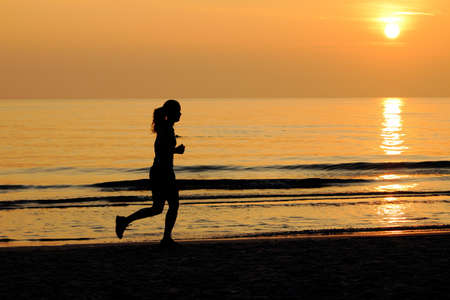 Sillouette of the woman jogging on the beach at sunset