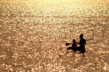 Silhouette family kayaking in the seaの写真素材