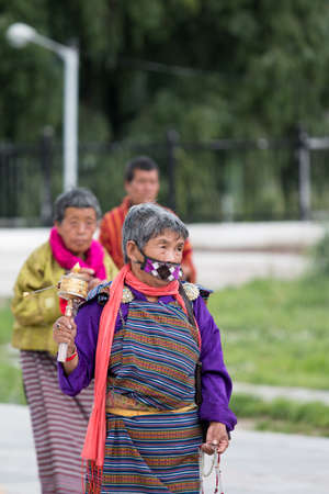 Old woman roll prayer wheel  THIMPHU, BHUTAN - JULY 12, 2013 in Thipmhuのeditorial素材