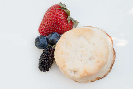 Scones with strawberries, blueberry and mulberry on white backgroundの写真素材
