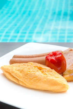 breakfast with omelet, sausages, ham, tomato, potatoes fried on white plateの写真素材