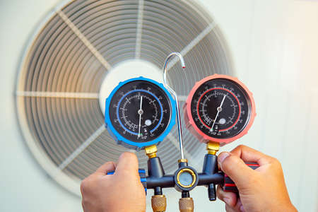Hands of Technician are using a measuring tool to check Vacuum pump evacuates air for air...