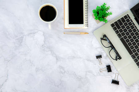 Top view desk,Modern office desk Workspace with laptop computer, coffee cup, glasses,notebook and office supplies for Working background concept.の写真素材