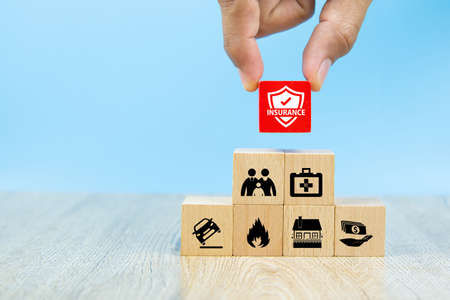 Close-up hand choose a red wooden toy blocks with insurance icon for safety family insurance