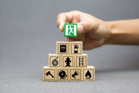 Close-up hand choose a wooden toy blocks with fire exit icon for fire safety protection concepts.の写真素材