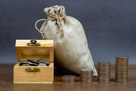 Many coins are stacked in a graph shape and many coins in a wooden crate for money saving ideas financial planning and insurance.の写真素材