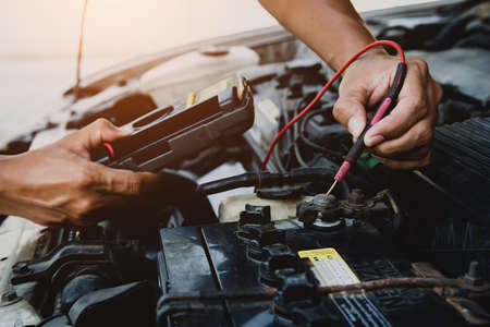 Auto mechanic using measuring equipment for checking car battery. Concepts of car Repair service and car insurance.の写真素材