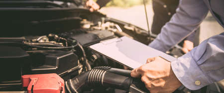 Auto mechanic using checklist for car engine systems after fixed. concepts of car insurance support...