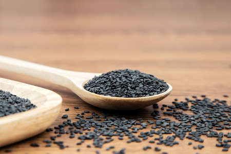 Black sesame seeds in a wooden spoon.の写真素材