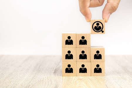 Close up hand choosing people icons on cube wooden toy blogs concepts human resources for business organizations and leadership.の写真素材
