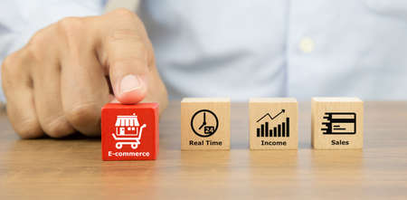 Close-up hand choosing cube wooden toy blocks with franchise business store and E-commerce icon. for...