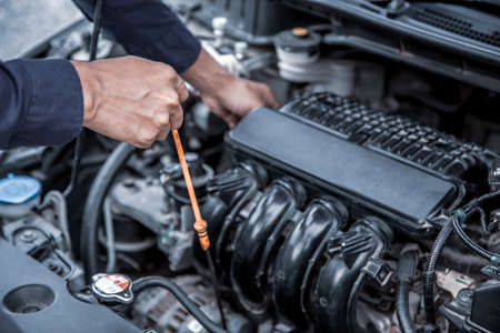 Auto mechanic checking vehicleâs engine oil level to changing car engine oil concepts of maintenance repair service and car insurance.の写真素材