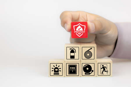 Close-up hand choose fire prevent icon on cube wooden toy blocks stacked with fire prevention icon for safety emergency concepts.の写真素材
