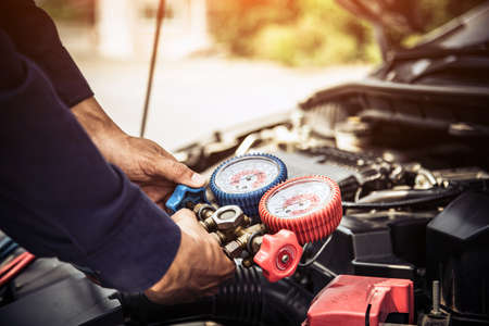 Auto mechanic using measuring equipment tool for filling car air conditioners fix checking. Concepts of car care repair service and insurance.の写真素材