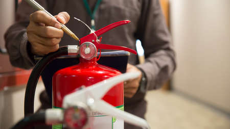 Fire fighter are checking pressure gauge of red fire extinguishers tank in the building