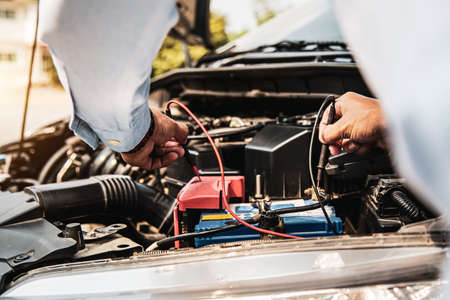 Auto mechanic using measuring equipment tool for fix checking car battery. Concepts of Old car...
