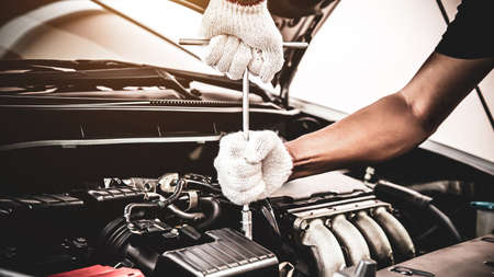 Close-up hands of auto mechanic are using the wrench to repair a car engine in auto car garage. Concepts of car care fixed repair and services.の写真素材