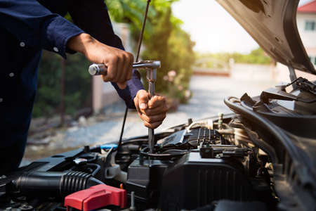 Close-up hands of auto mechanic are using the wrench to repair a car engine in auto car garage. Concepts of car care fixed repair and services.の写真素材
