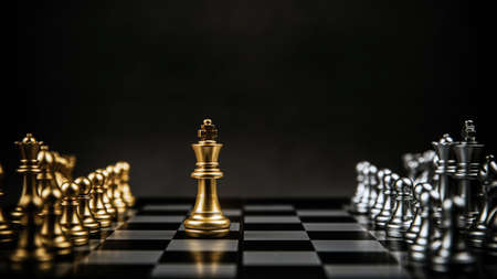 King golden chess standing confront of the silver chess team to challenge on chess board. Concept of business team and strategic plan, leader and strategy of risk management.の写真素材