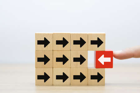 Wooden toy blocks stacked with arrow icon pointing to opposite directions for way of business change.の写真素材