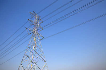 High-voltage transmission tower and electricity voltage wiring cable with sky background.の写真素材
