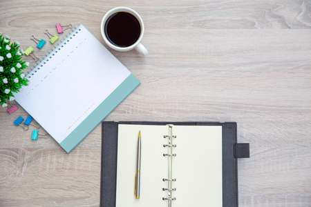The top view desk and blank calendar with a pen and office equipment for working area copy space...