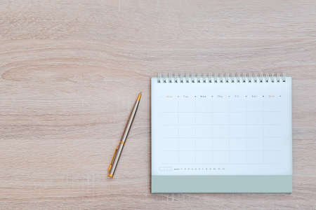 The top view desk and blank calendar with a pen and office equipment for working area copy space composition and work from home concepts.の写真素材