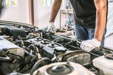 Close-up hands of auto mechanic are using the wrench to repair and maintenance auto engine is...