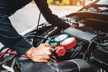 Close up hand of auto mechanic are to use measuring manifold gauge for filling car air conditioners. Concepts of fix and checking for repair service and car insurance.の写真素材