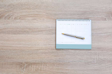 The top view desk and blank calendar with a pen and office equipment for working area copy space composition and work from home concepts.の写真素材