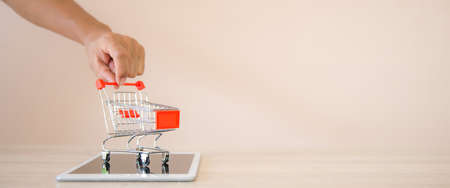 Close up hands pushing the shopping cart on smart phone or tablet at desk concept of using the application for spending and online shopping at home.の写真素材